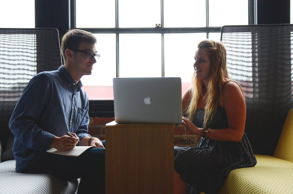Dos profesionales colaborando en un entorno de oficina productivo, evidenciando las relaciones interpersonales en el trabajo a través de la comunicación efectiva y el trabajo en equipo.