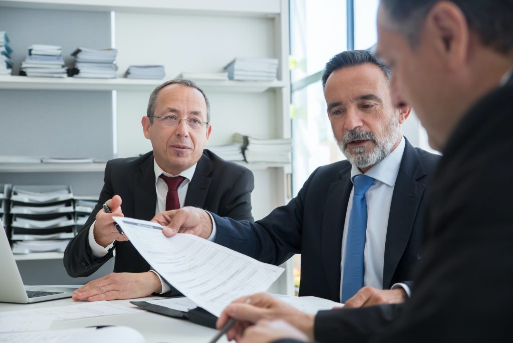 Directivos en reunión estratégica analizando documentos, aplicando principios de psicología positiva para optimizar la toma de decisiones y el liderazgo ejecutivo.